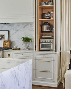 a white kitchen with marble counter tops and cabinets in the corner, along with an open shelving unit