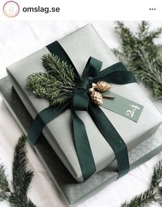 two wrapped presents with green ribbon and pine cones