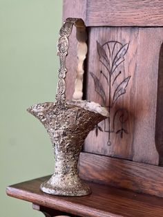 an ornate silver vase sitting on top of a wooden shelf