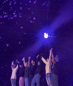 a group of people standing on top of a stage holding their hands in the air