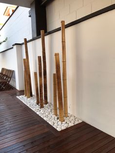 several bamboo poles are lined up against the wall with white rocks and pebbles in between them