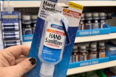 a hand sanitizer is being held up by a person in a store aisle