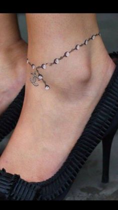 a woman's foot with a cross and pearls on it