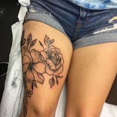 a close up of a person's thigh with tattoos on it and flowers around the thighs