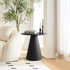 a living room with a white couch, black table and potted plant in the corner