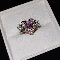 a purple heart shaped ring in a white box with pink and silver accents on it