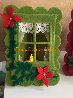 a small christmas window with poinsettis and lace on the windowsill is decorated in green felt