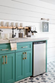 a kitchen with teal cabinets and black and white tile flooring on the walls