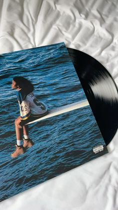 a person on a surfboard in the water with an album cover over their shoulder