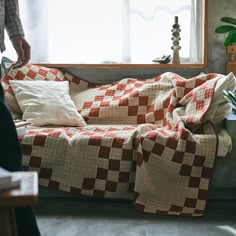 a person standing next to a couch covered in a checkered blanket