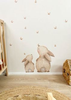 two rabbits sitting on the ground in front of a wall with butterflies flying above them