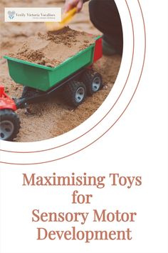 a green toy truck filled with dirt next to a child's hand in the sand