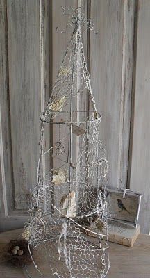 a small wire christmas tree on a table next to a bird nest and other items