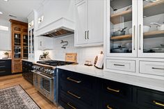 a kitchen with black and white cabinets, wood flooring and an area rug on the floor