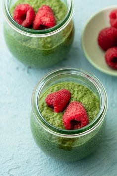 two small jars filled with green smoothie and raspberries on top of each other