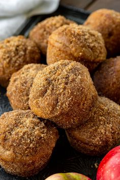 apples and cinnamon sugar muffins on a black plate next to an orange apple