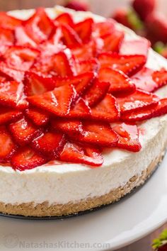 a cheesecake topped with sliced strawberries on top of a white cake platter