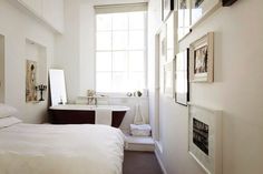 a bedroom with a bathtub, sink and window in the wall next to it