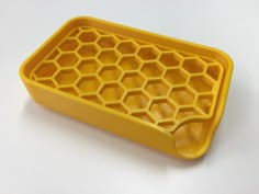 a yellow plastic tray with honeycombs on the bottom and sides, sitting on a white surface