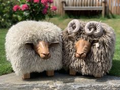 two sheep statues sitting on top of a stone slab