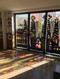 the sun shines through stained glass windows in an empty room with art work on it