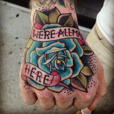 a person with a rose tattoo on their hand and the words we're all in here