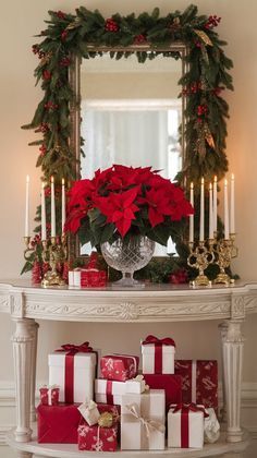 a white table topped with lots of presents under a christmas wreath and candlelight mirror