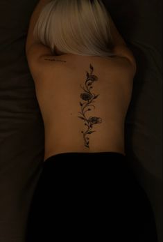 a woman laying in bed with her back turned to the camera and tattoos on her body