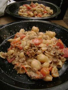 two black plates filled with pasta and meat