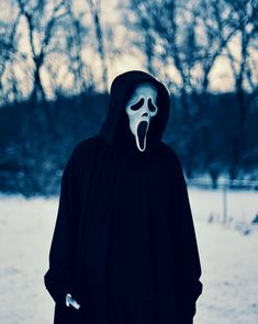 a person in a black hoodie with a white mask on and his mouth open