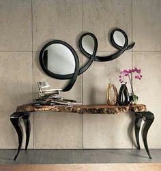 a wooden table topped with a mirror next to a vase filled with flowers and books