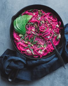 a skillet filled with beetroot noodles and avocado