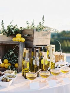 a table topped with lots of bottles and glasses filled with wine next to lemons