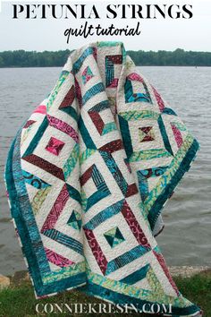 a quilted blanket sitting next to the water