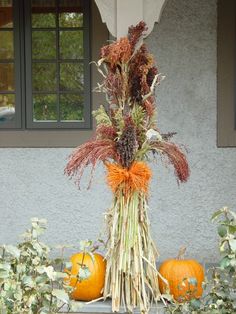 an arrangement of dried flowers and pumpkins in front of a house