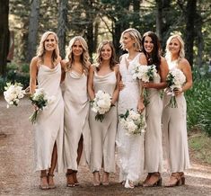 a group of women standing next to each other in front of trees and flowers on the ground