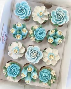 cupcakes decorated with blue and white flowers in a box