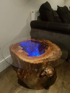 a glass table with a wood stump base and blue light in the center, sitting on a hard wood floor