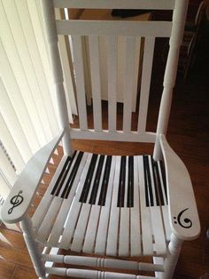 a white rocking chair with black and white piano keys on it's back legs