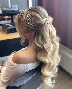 a woman with long blonde hair is sitting in a chair and wearing a headpiece