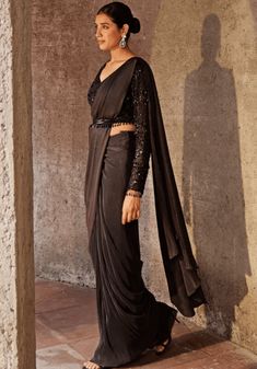 Introducing the Black Pre Drape Saree Set - an exquisite blend of elegance and convenience. This stunning black drape saree is crafted from a comfortable pleated fabric, ensuring effortless draping. The accompanying full-sleeved blouse features delicate tonal bead work in a mesmerizing floral pattern. To add the perfect finishing touch, this set includes a tasselled belt. With its ready-to-wear design, this ensemble offers both style and ease. Embrace sophistication with the Black Pre Drape Saree Set. Composition : Saree and Blouse -Pleated Blend, Lining - Shantoon Care: Dry Clean Only and Vacuum Storage This product can be customized for sleeves, length of blouse and neckline Delivery : 6-8 weeks as the product is hand crafted. Check Size Guide or choose MySize for free customisation (All Black Drape Saree, Saree And Blouse, Vacuum Storage, Drape Saree, Black Drapes, Indian Wedding Wear, Blouse For Women, Pleated Fabric, Fashion App