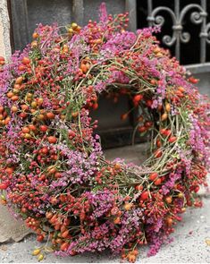 a wreath made out of flowers sitting on the ground next to a building with an iron gate