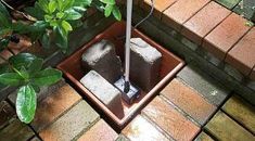 an umbrella sitting in a potted planter on the side of a brick walkway