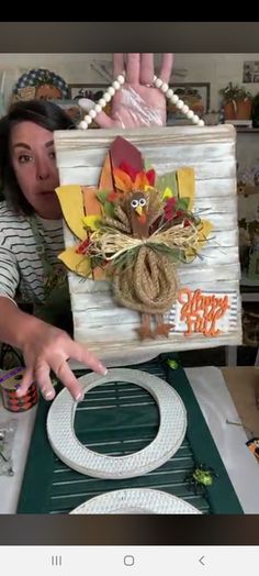 a woman is holding up a wooden box with a turkey decoration on it