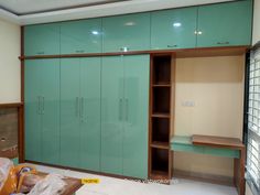 an empty room with green cupboards and shelves in the middle, including a bed