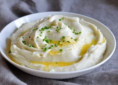 a white bowl filled with mashed potatoes on top of a gray table cloth and topped with green sprinkles