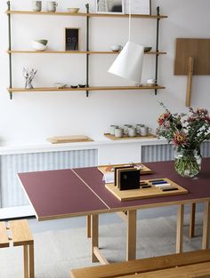 there is a table and bench in the room with shelves on the wall behind it