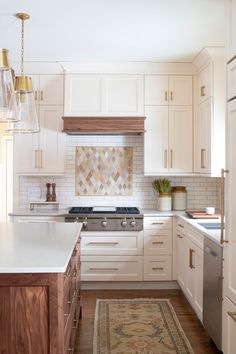 a kitchen with white cabinets and an area rug in front of the stove top oven