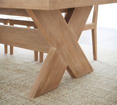 a close up view of a wooden table with two benches in the center and an area rug on the floor