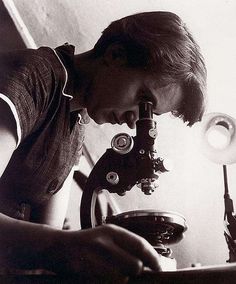 a boy looking through a microscope at something in the distance with his hand on it